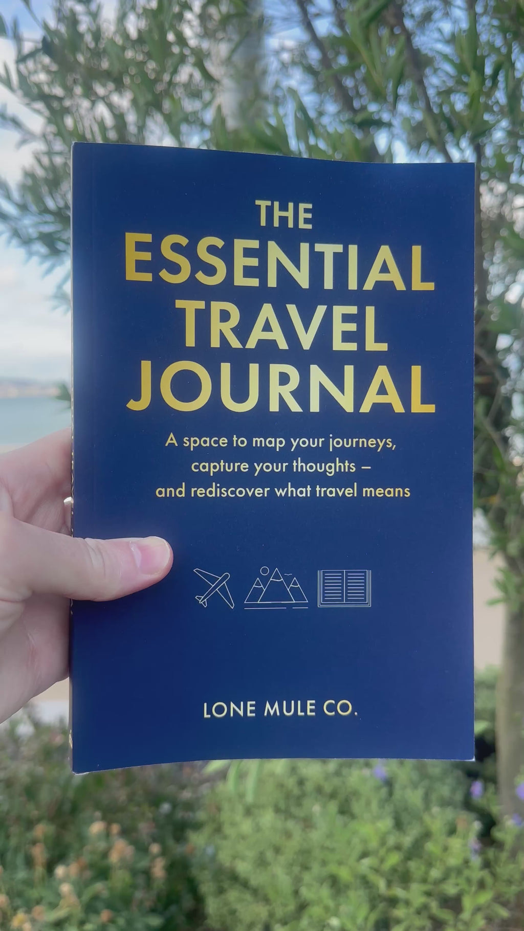 Navy & Gold Essential Travel Journal by Lone Mule Co. shown as a physical paperback copy.